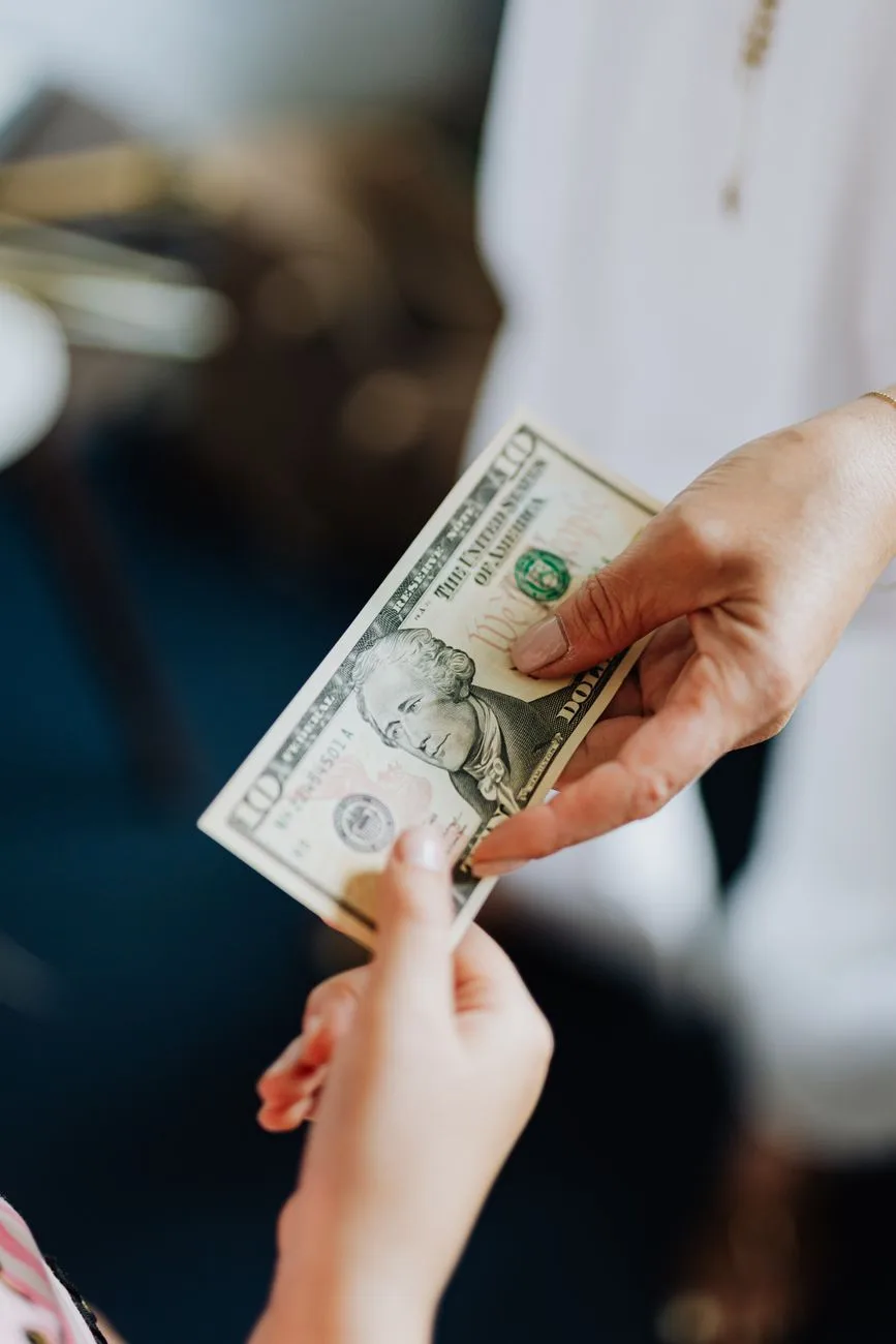 Foto de una persona dandole dolares a otra persona